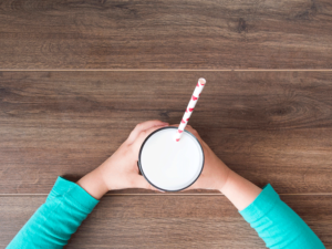A glass of milk with a straw in it.