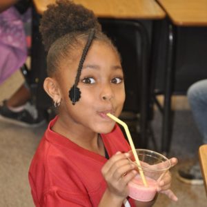 A girl sipping on a pink smoothie