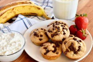 A plate of fresh chocolate chip muffins made with blended cottage cheese served with strawberries and a glass of milk
